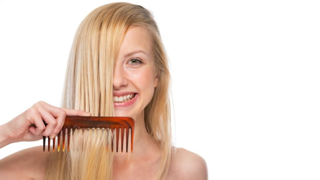 Smiling blonde woman combing her hair in front of her face