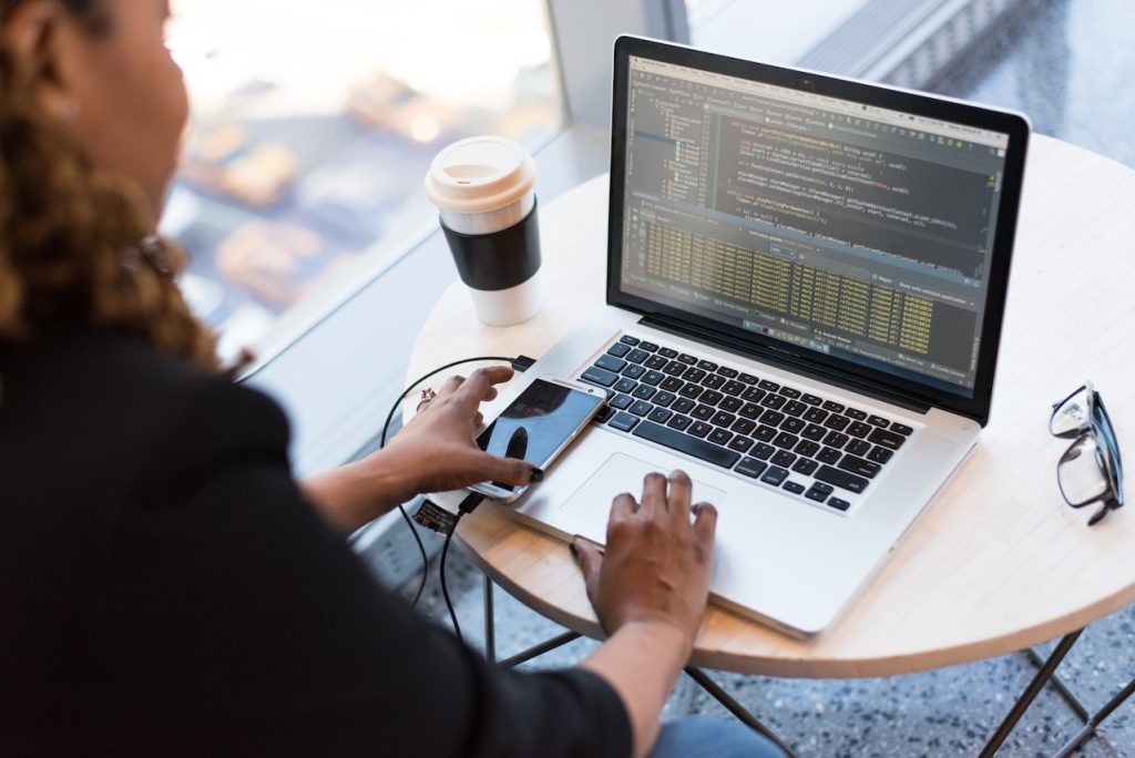 woman with phone on her open laptop