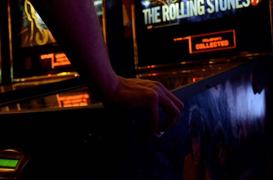 Hands shown playing a pinball arcade machine