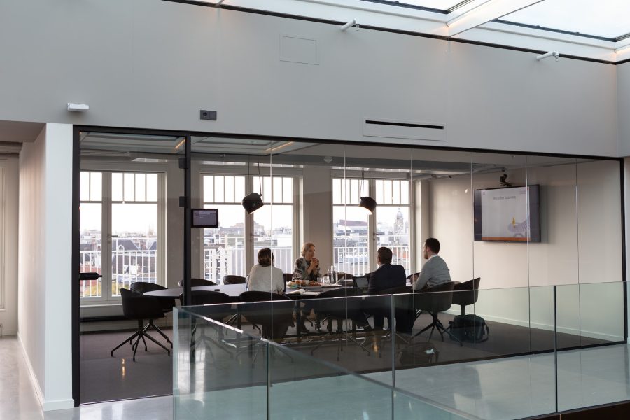 Glass-enclosed board room with four people