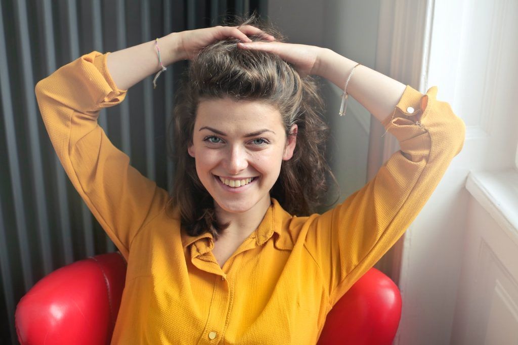 woman seated holding hands on top of head