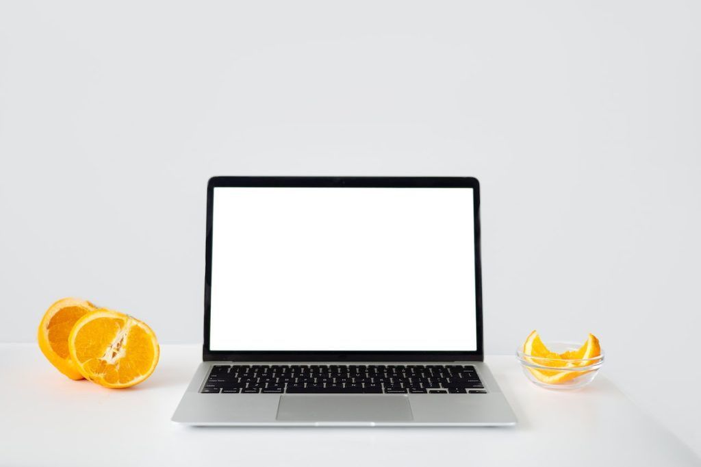 laptop with blank screen surrounded by some oranges