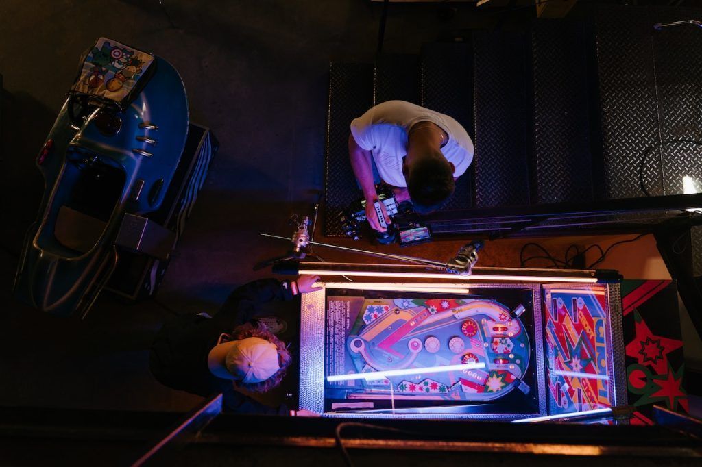 Overhead view of two men and a pinball machine