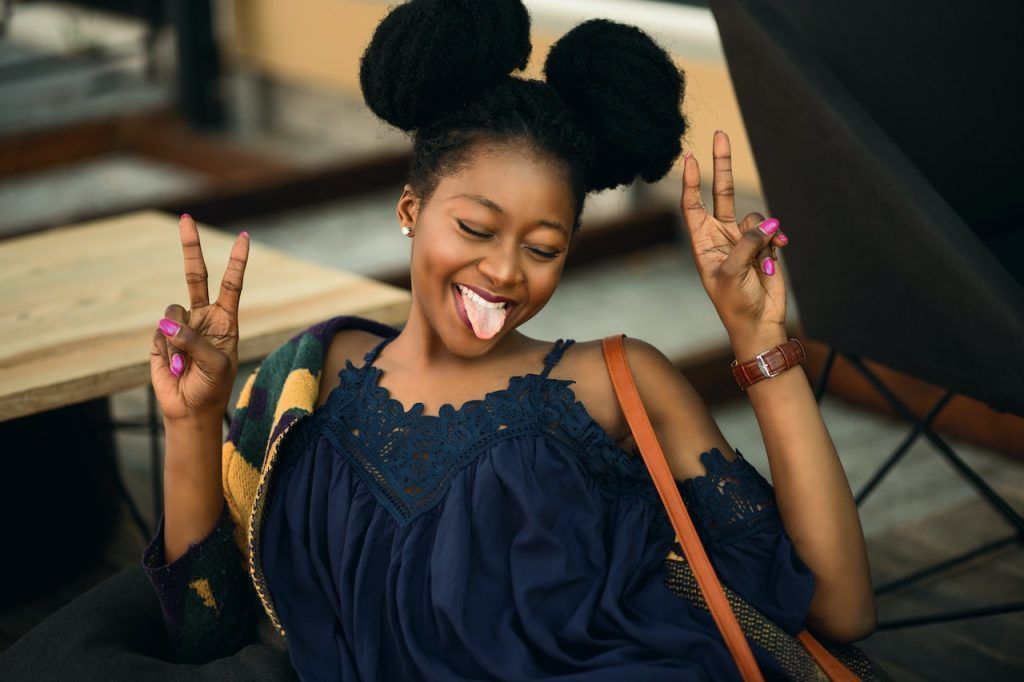 woman joyfully sticking her tongue out and putting two fingers up on each hand