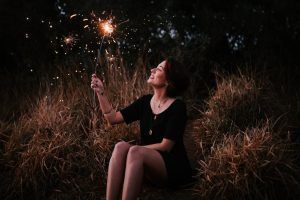woman seated outside holding a sparkler
