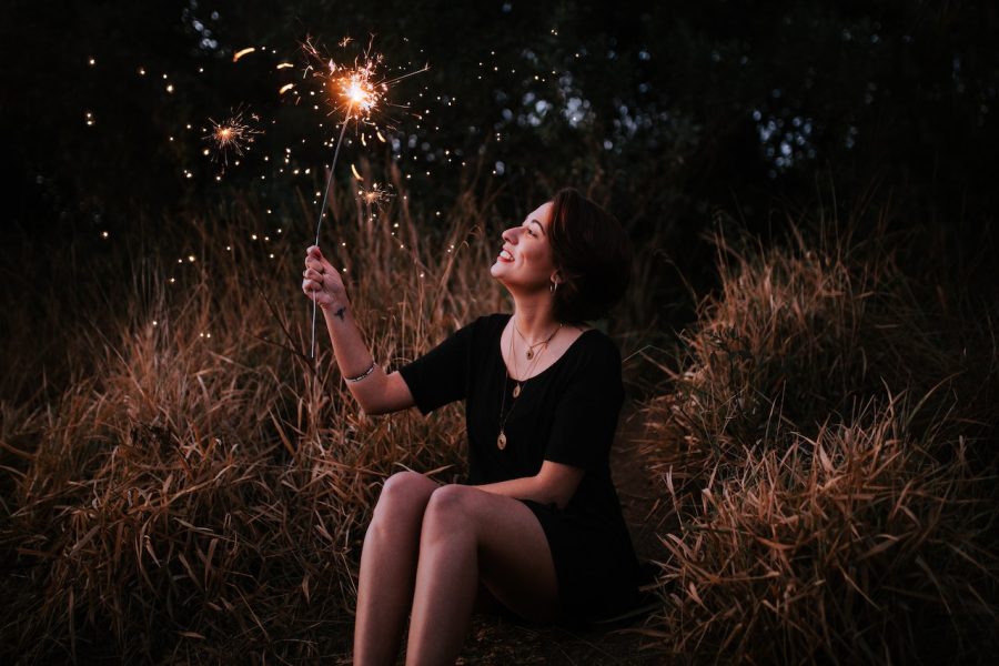 woman seated outside holding a sparkler