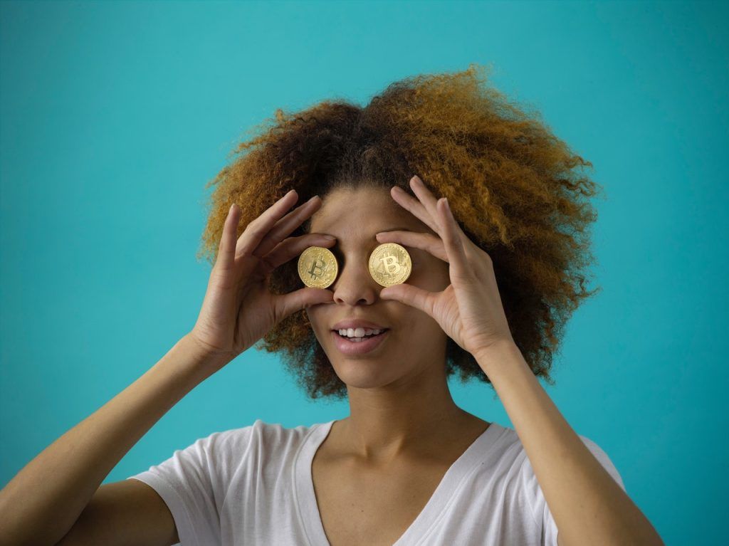 Woman holding physical bitcoins in front of eyes