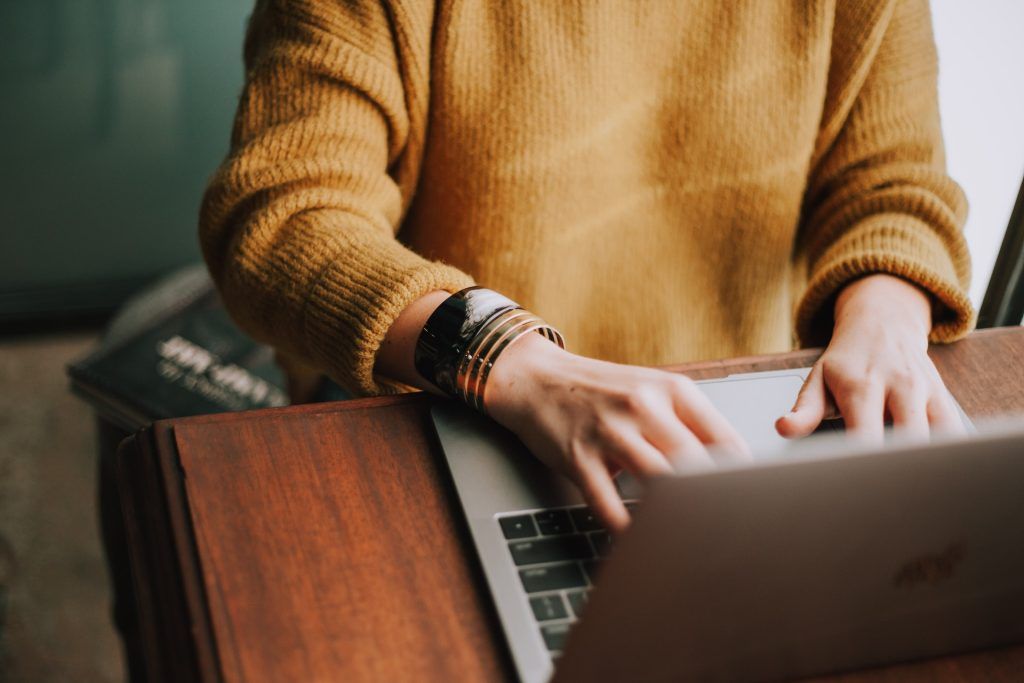 Many with yellow sweater typing on a laptop