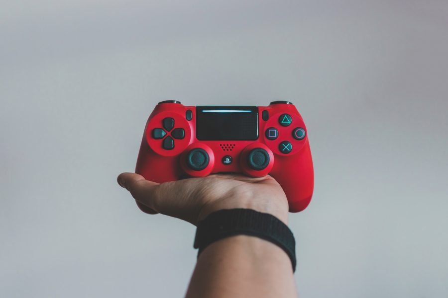 Hand holding up a red PlayStation controller against a white background