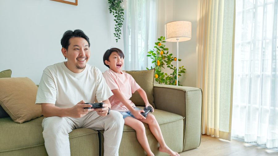 Man and boy playing videogames from a sofa