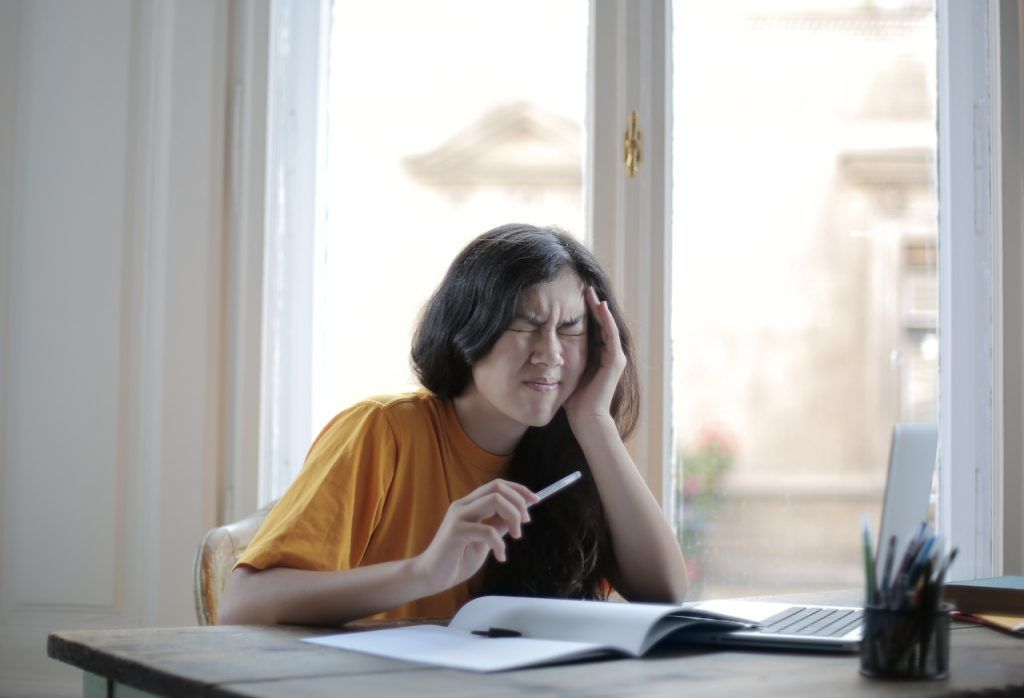 Woman in pain in front of notebook and computer