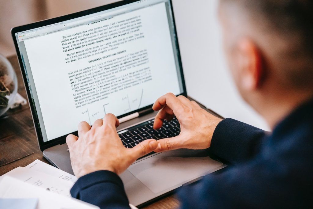 Man typing a document on a laptop screen