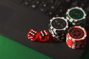 Poker chips and red dice on the corner of a laptop