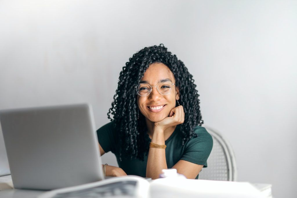 Woman with glasses looking at the viewer in front of a laptop