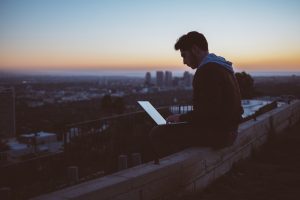 man on roof playing on his laptop