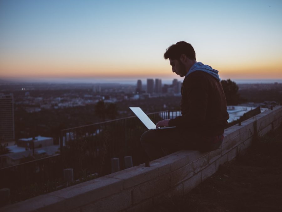 man on roof playing on his laptop