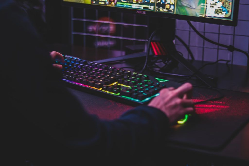 man playing computer games with an RGB keyboard and mouse