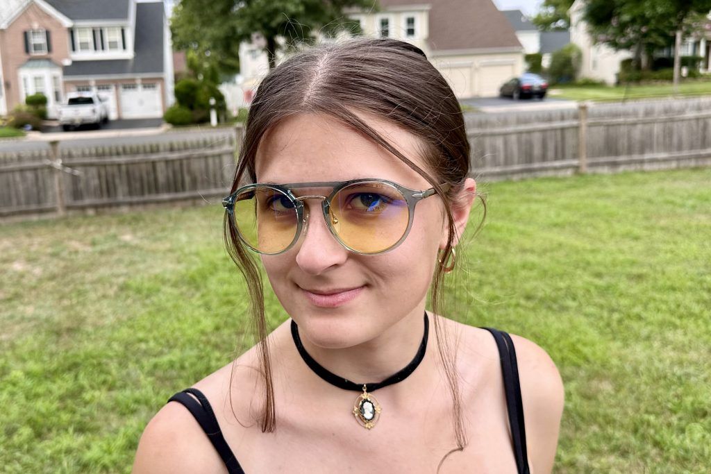 A young woman wearing Warcraft, Alliance Edition glasses outside