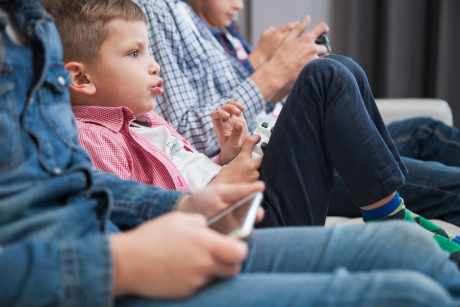 Boy playing video games near crop siblings. Image from: Freepik