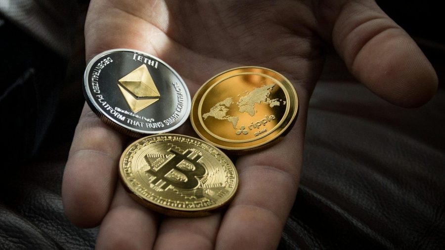 hand holding three different physical bitcoins