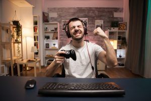 Pov of happy young man celebrating his victory on online shooter game using wireless controller