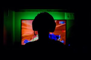 A Gamer playing in a dark room with a greenish glow