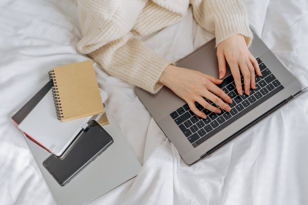 High-Angle Shot of a Person Using His Laptop on the Bed