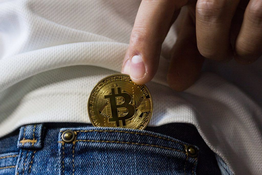 gold bitcoin being removed from pocket of jeans