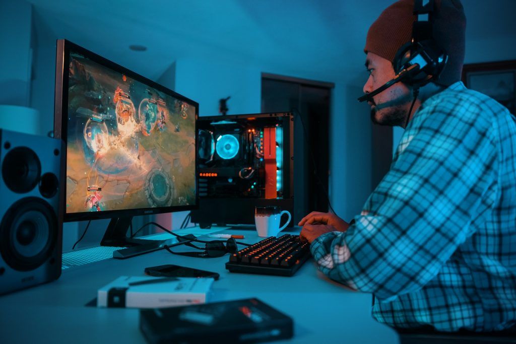 side view of a person wearing headphones and using a computer to play games