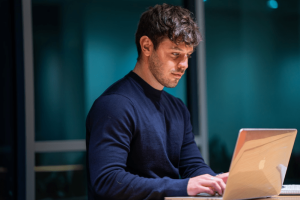 A man working at a desk with a laptop, emphasizing the significance of effective request proposal in business.