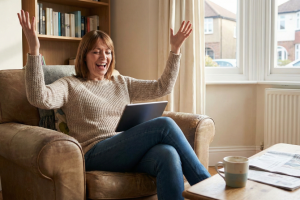 Middle aged woman declaring victory playing a game on her tablet.