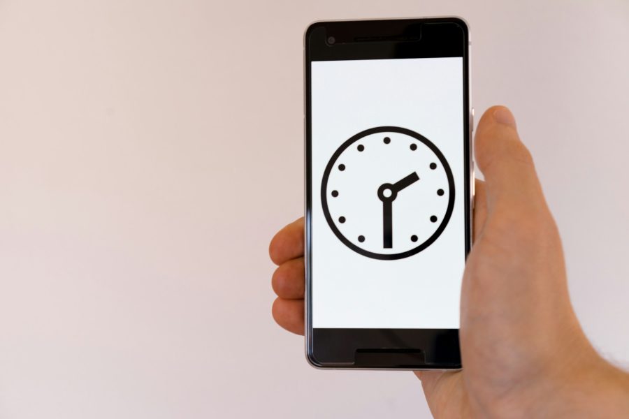 person holding black android smartphone with clock on front