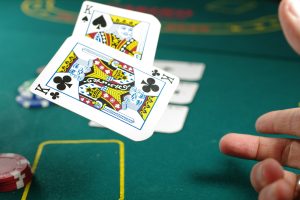 person tossing two poker cards at casino table