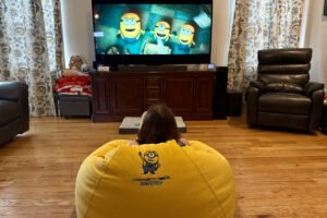 Girl watching a Minions movie as she sits on the AndaSeat Minions Cloud Bean Bag Gaming Sofa.
